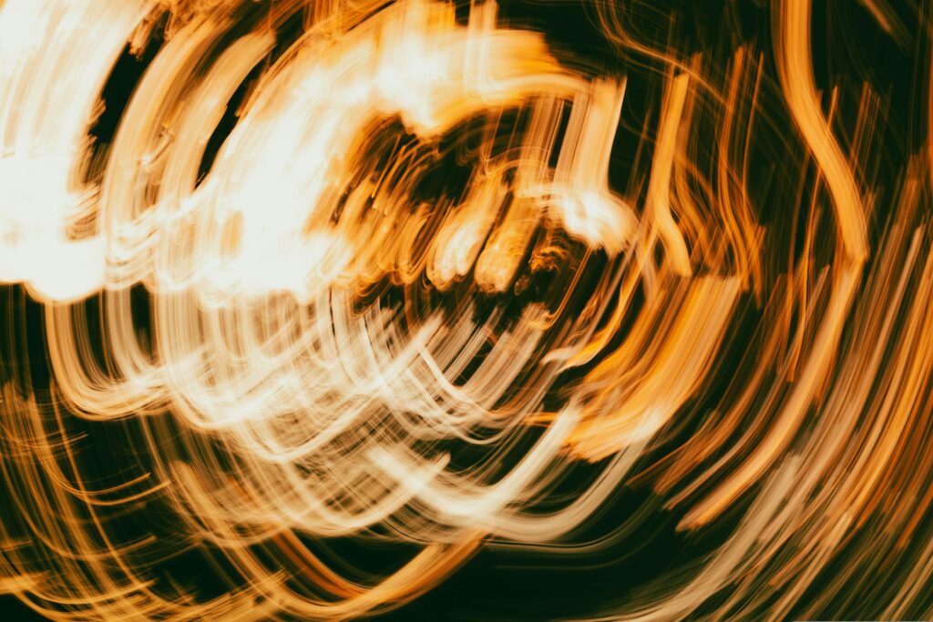 Vibrant abstract image featuring dynamic light trails and swirling patterns in warm colors.